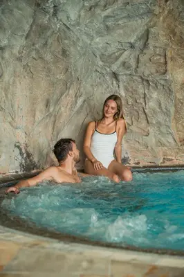 a man and a woman sitting in a swimming pool at Residence Mühlegg in Valdaora