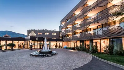 a building with a fountain in the middle of a courtyard at Hotel Rosengarten (Schenna Resort) in Schenna