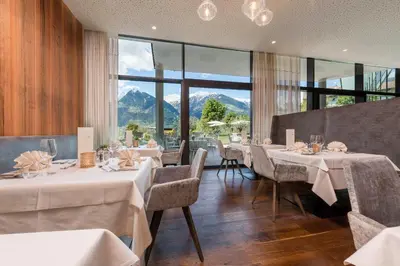 a restaurant with tables and chairs and a large window at Hotel Rosengarten (Schenna Resort) in Schenna