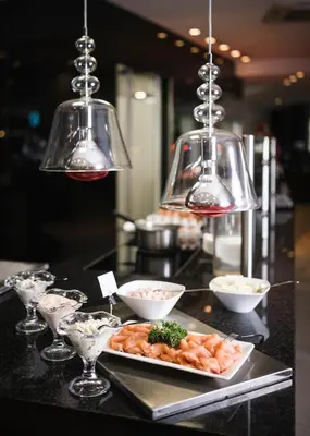 a plate of food on a counter with three lights at Hotel Rosengarten (Schenna Resort) in Schenna