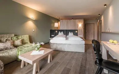a hotel room with a bed and a couch at Hotel Rosengarten (Schenna Resort) in Schenna
