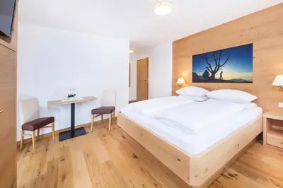 a bedroom with a large bed and a desk at Hotel Garni Morene in Selva di Val Gardena
