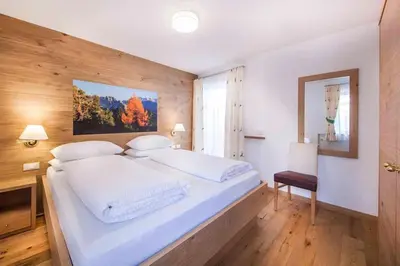 a bedroom with a large white bed and a desk at Hotel Garni Morene in Selva di Val Gardena