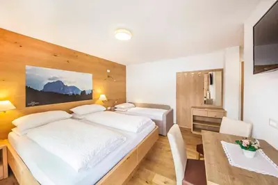 a bedroom with a large white bed and a table at Hotel Garni Morene in Selva di Val Gardena