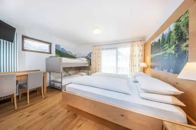 a bedroom with a large bed and a desk at Hotel Garni Morene in Selva di Val Gardena