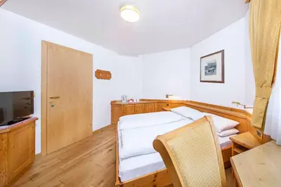 a bedroom with a bed and a table and a television at Hotel Garni Morene in Selva di Val Gardena