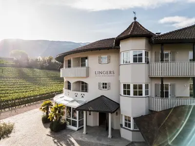 a building with a vineyard in the background at Lingers Suites & Residence in Appiano sulla Strada del Vino