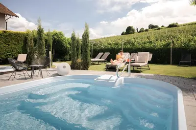 a woman sitting in a chair next to a swimming pool at Lingers Suites & Residence in Appiano sulla Strada del Vino