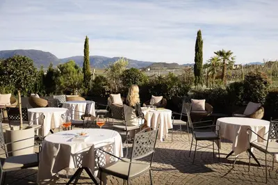 a restaurant with tables and chairs with mountains in the background at Lingers Suites & Residence in Appiano sulla Strada del Vino