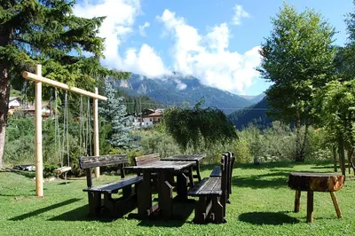 a picnic table and chairs in a field with mountains at Appartamenti Casari in Pozza di Fassa