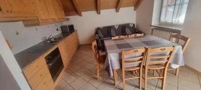 a kitchen with a table and chairs in a room at Appartamenti Casari in Pozza di Fassa