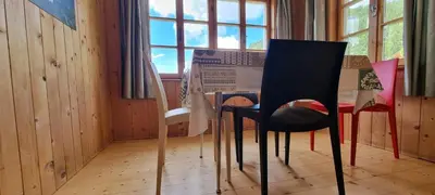 a dining room with chairs and a table and a window at Appartamenti Casari in Pozza di Fassa