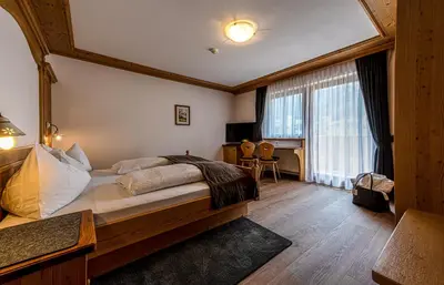 a bedroom with a large bed and a desk in it at Garni Sunela B&B in Selva di Val Gardena
