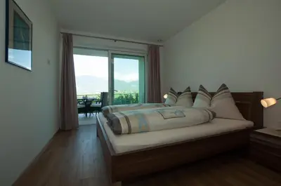 a bedroom with a bed and a large window at Oberberghof in Appiano sulla Strada del Vino