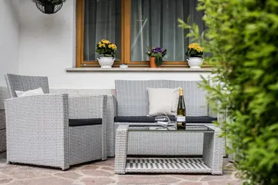 a bottle of wine sitting on a wicker chair on a patio at Apartment Rainer in Ortisei