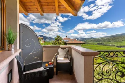 a balcony with chairs and a view of the mountains at Relais Villa Quercia in Tassullo