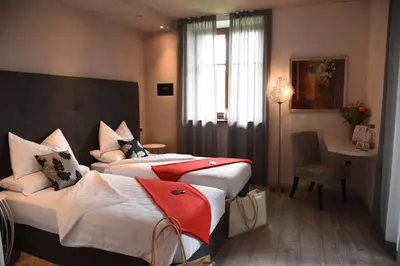 a hotel room with two beds and a desk at Relais Villa Quercia in Tassullo