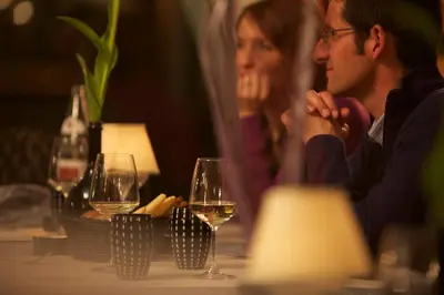 a man and woman sitting at a table with wine glasses at Hotel Castel Pietra in Fiera di Primiero