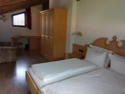 a bedroom with a large white bed and a desk at Hotel Castel Pietra in Fiera di Primiero