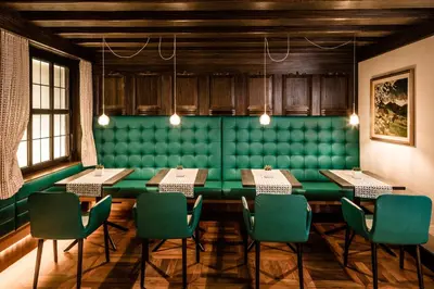 a dining room with a green table and chairs at Hotel Haus am Hang in Caldaro