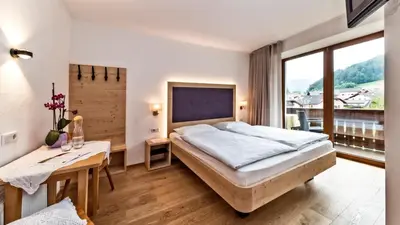 a bedroom with a bed and a table and a window at Garni Pramstrahler in Chiusa
