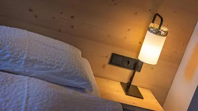 a bedroom with a bed and a lamp on a table at Garni Pramstrahler in Chiusa