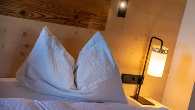 two pillows sitting on top of a bed next to a lamp at Garni Pramstrahler in Chiusa