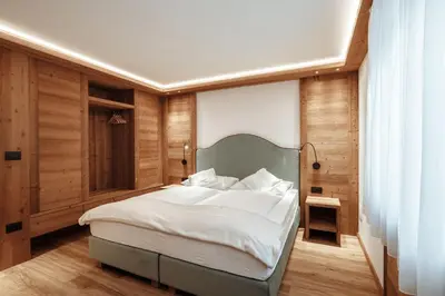 a bedroom with a large bed with a green headboard at Appartamenti Insam in Santa Cristina in Val Gardena