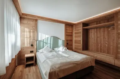 a bedroom with a bed with a wooden wall at Appartamenti Insam in Santa Cristina in Val Gardena
