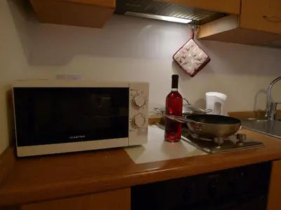 a microwave on a kitchen counter with a bowl and a bottle of wine at Appartamento San Marco in Caprile