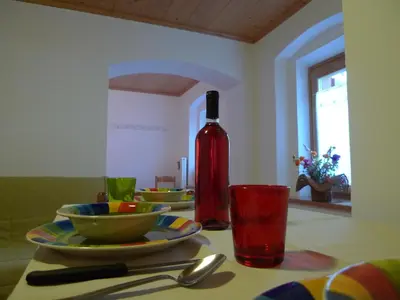 a table with a bottle of wine and dishes on it at Appartamento San Marco in Caprile