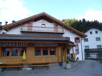 a restaurant with benches in front of a building at Appartamento San Marco in Caprile