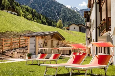 a group of chairs sitting in the grass next to a building at Hotel Almina in Racines