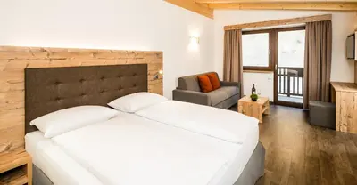 a bedroom with a large white bed and a chair at Hotel Almina in Racines