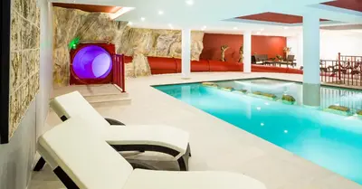 a hotel pool with two chairs and a tv at Hotel Almina in Racines