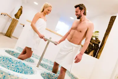 a man and a woman in white towels on a swimming pool at Hotel Almina in Racines