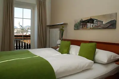 a bedroom with a green and white bed with a window at Gasthof Albergo Kreuzwirt in Fiè