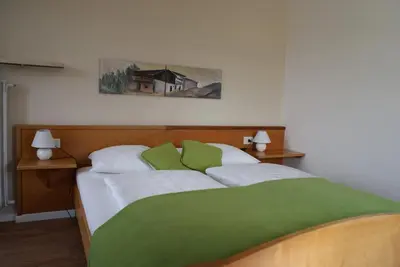 a bedroom with a bed with green and white pillows at Gasthof Albergo Kreuzwirt in Fiè