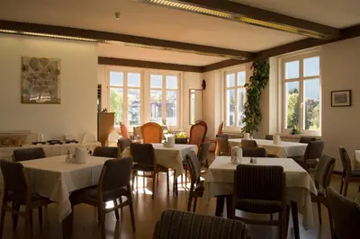 a restaurant with white tables and chairs and windows at Gasthof Albergo Kreuzwirt in Fiè