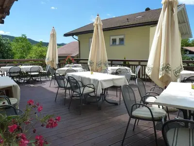 a group of tables and chairs with umbrellas on a deck at Gasthof Albergo Kreuzwirt in Fiè