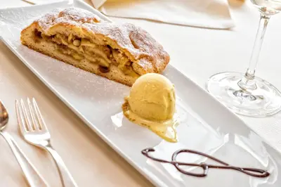 a plate with a pastry and ice cream on a table at Hotel Armin in Selva di Val Gardena