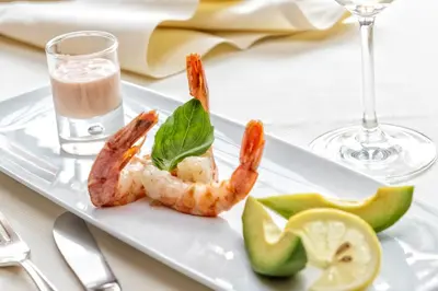 a plate of shrimp with a glass of wine and a drink at Hotel Armin in Selva di Val Gardena