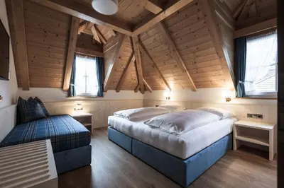 two beds in a room with wooden ceilings and windows at Residence Villa Stella in Ortisei