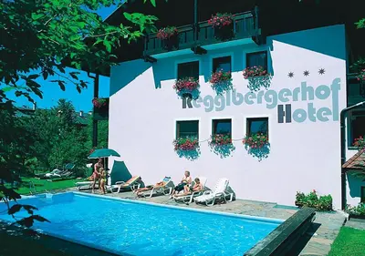 a hotel with people sitting in chairs next to a swimming pool at Hotel Regglbergerhof in Nova Ponente