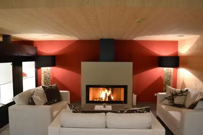 a living room with red walls and a fireplace at Hotel Regglbergerhof in Nova Ponente
