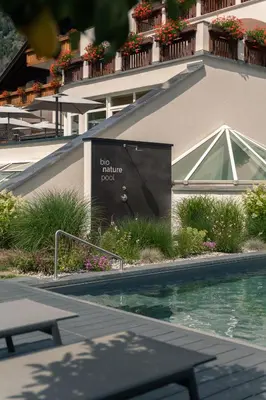 a table with a drink on it next to a pool at Hotel WH - Wiesnerhof in Vipiteno
