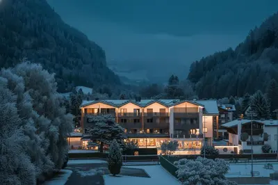 a large building with cars parked in a parking lot at Hotel WH - Wiesnerhof in Vipiteno