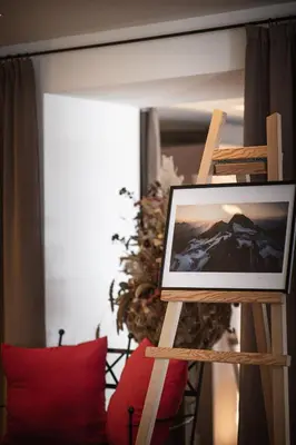 a picture frame on a stand next to a red pillow at Hotel Mühlwald in Selva dei Molini