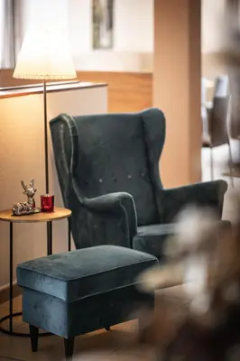 a living room with a chair and a table and a lamp at Hotel Mühlwald in Selva dei Molini