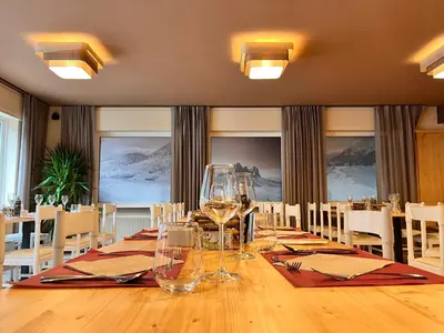 a dining room with a long table with wine glasses at Hotel Rododendro Val di Fassa in Campitello di Fassa
